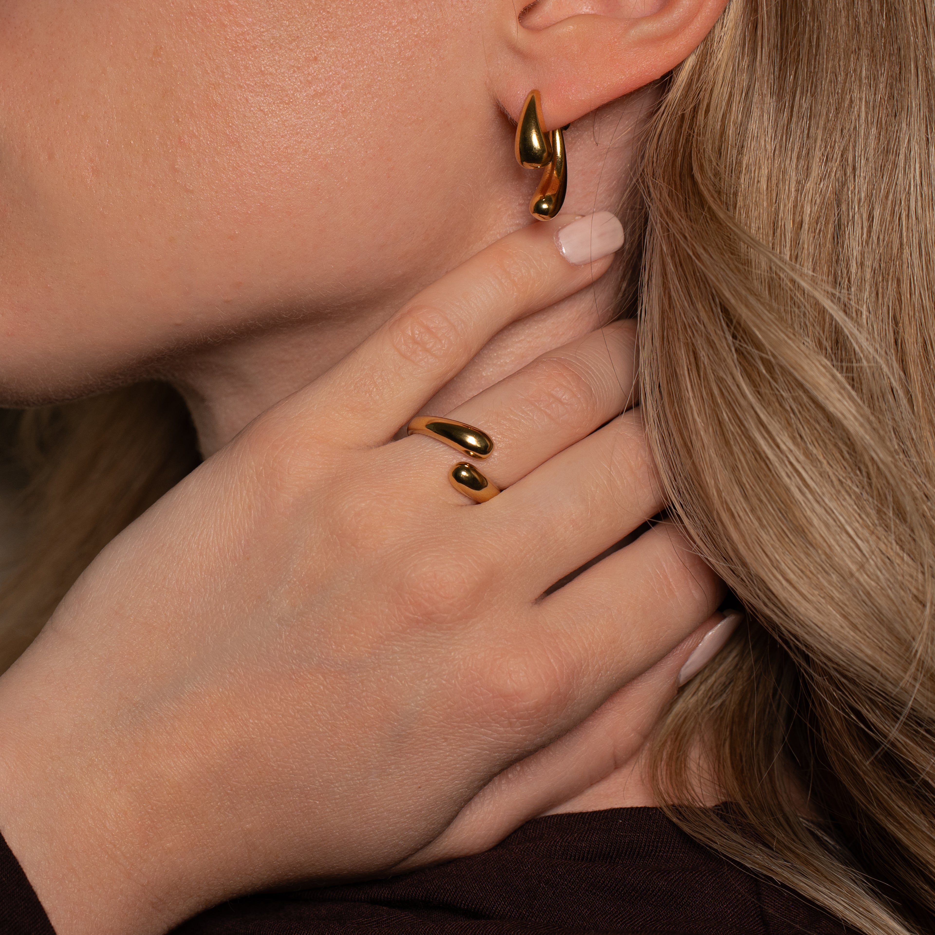 Frau die den Amar Ring in gold mit zwei Tropfenförmigen Enden an ihrem Finger trägt.