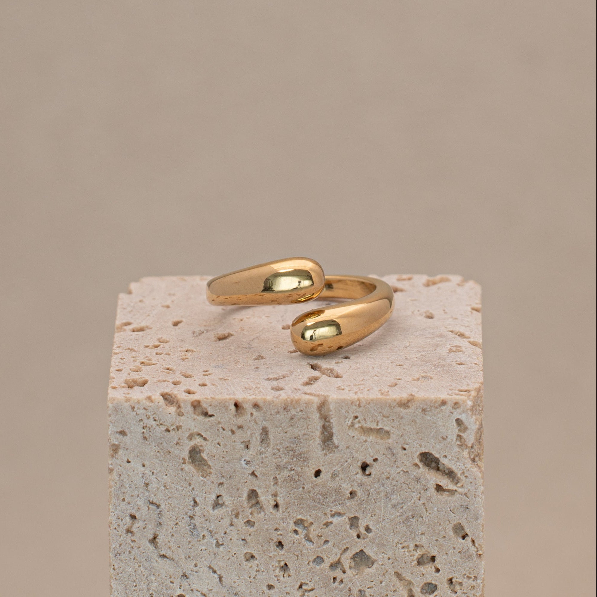 Amar Ring in gold mit zwei Tropfenförmigen Enden, liegend auf einem Stein.