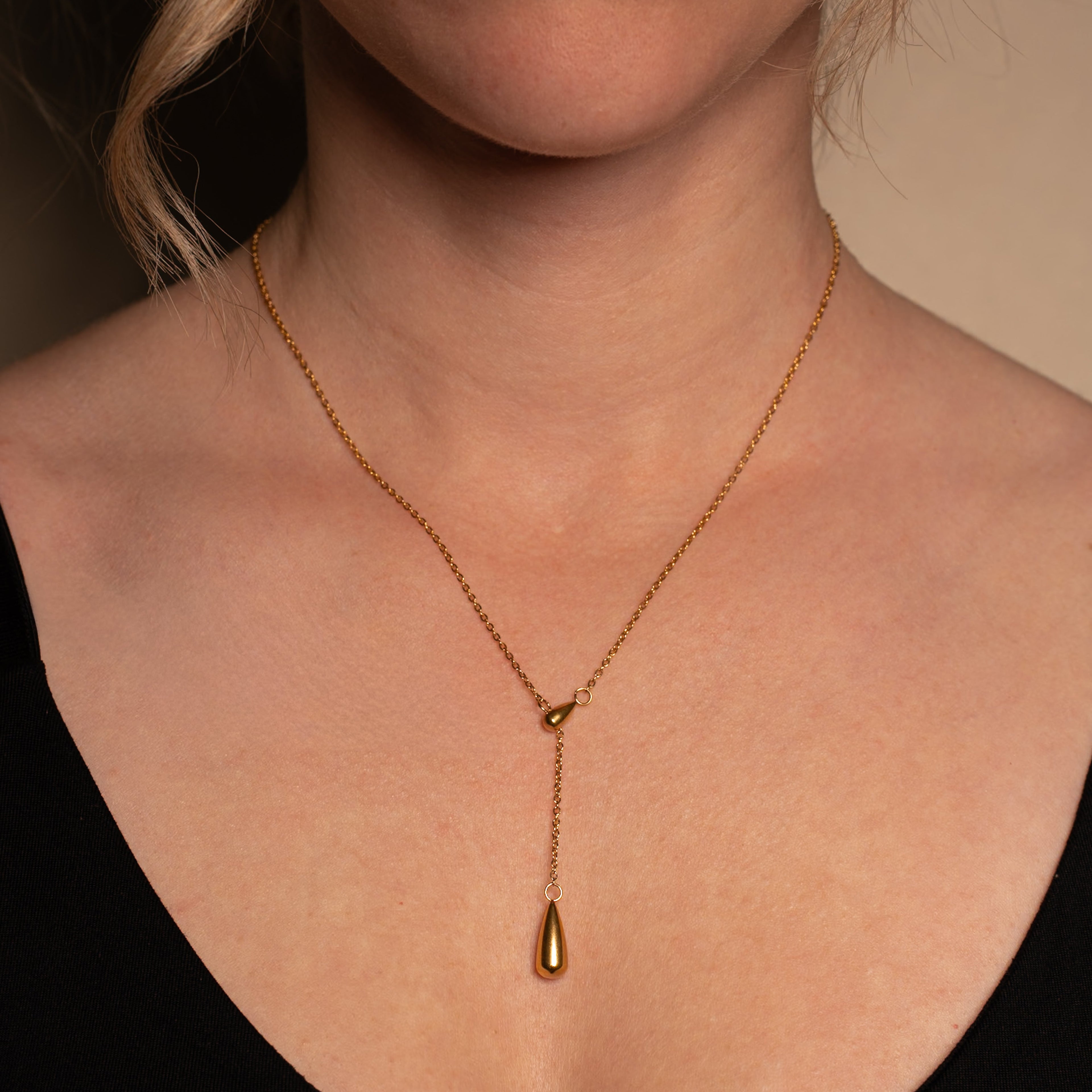 Ariel Halskette im gold mit einer Y-Kette und Tropfenanhänger getragen an einer Frau.