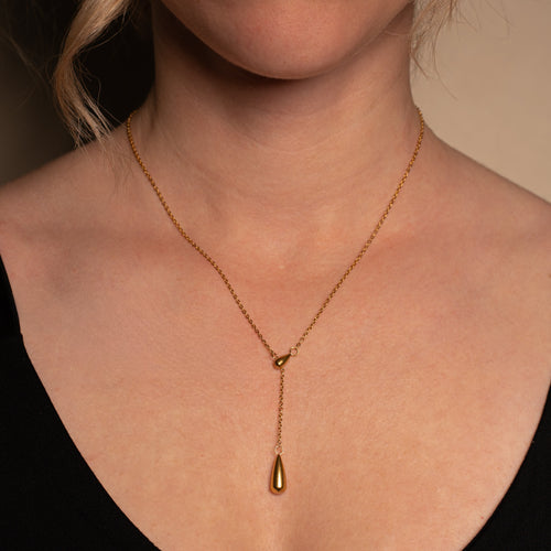 Ariel Halskette im gold mit einer Y-Kette und Tropfenanhänger getragen an einer Frau.