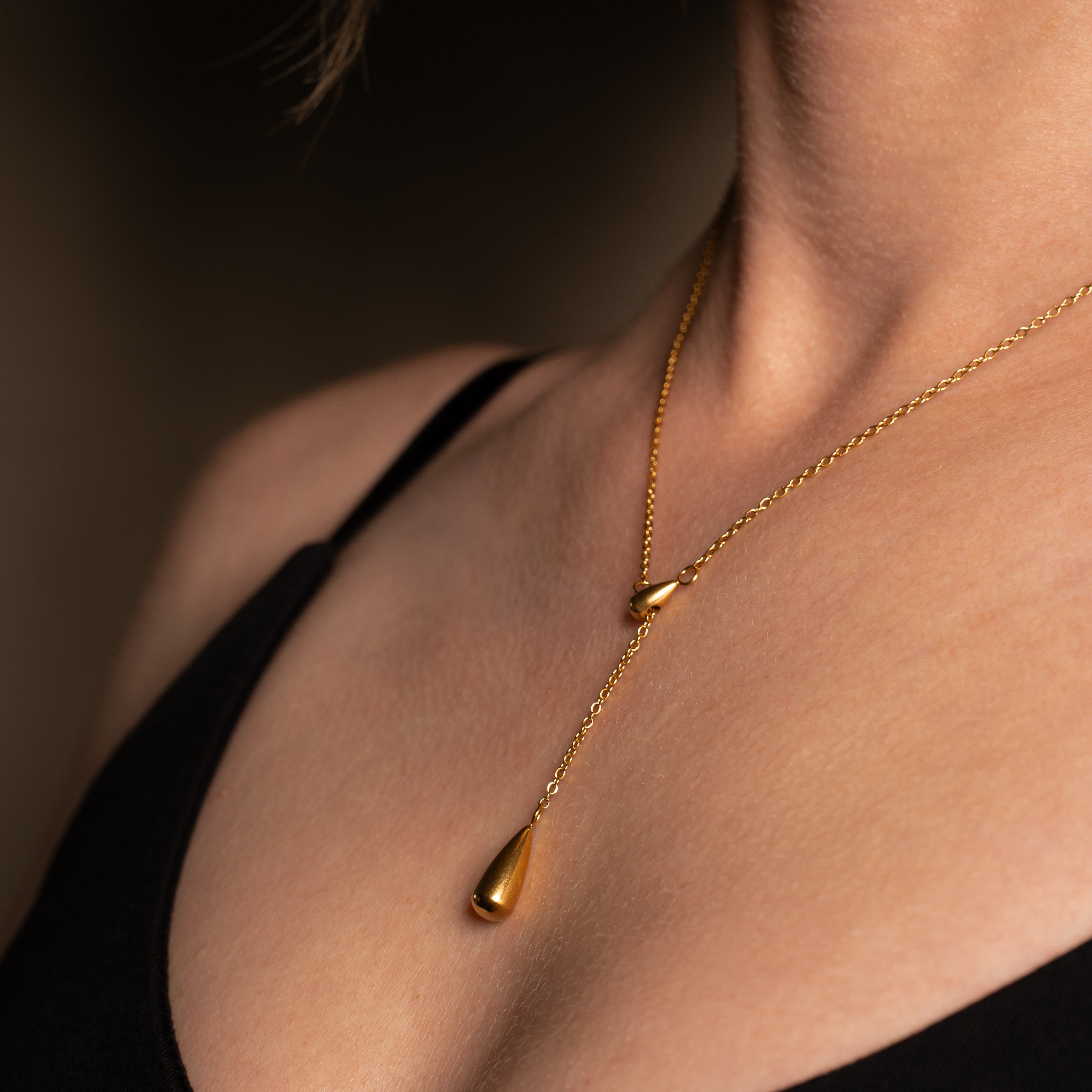 Ariel Halskette im gold mit einer Y-Kette und Tropfenanhänger getragen an einer Frau.