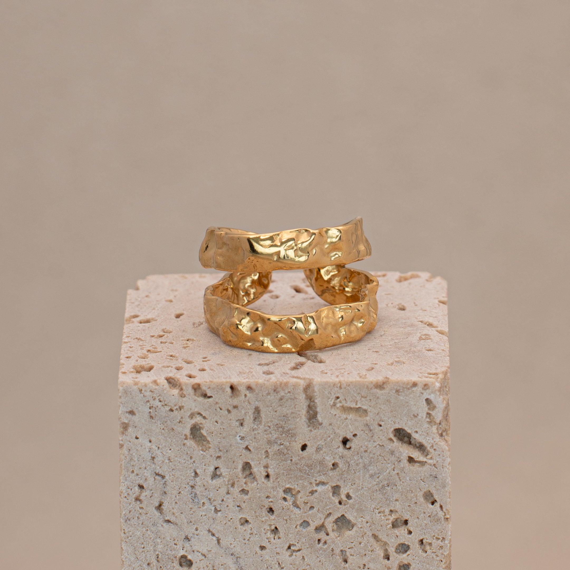 Brisa Ring in Gold mit zwei Reihen in organischem Look, liegend auf einem Stein.
