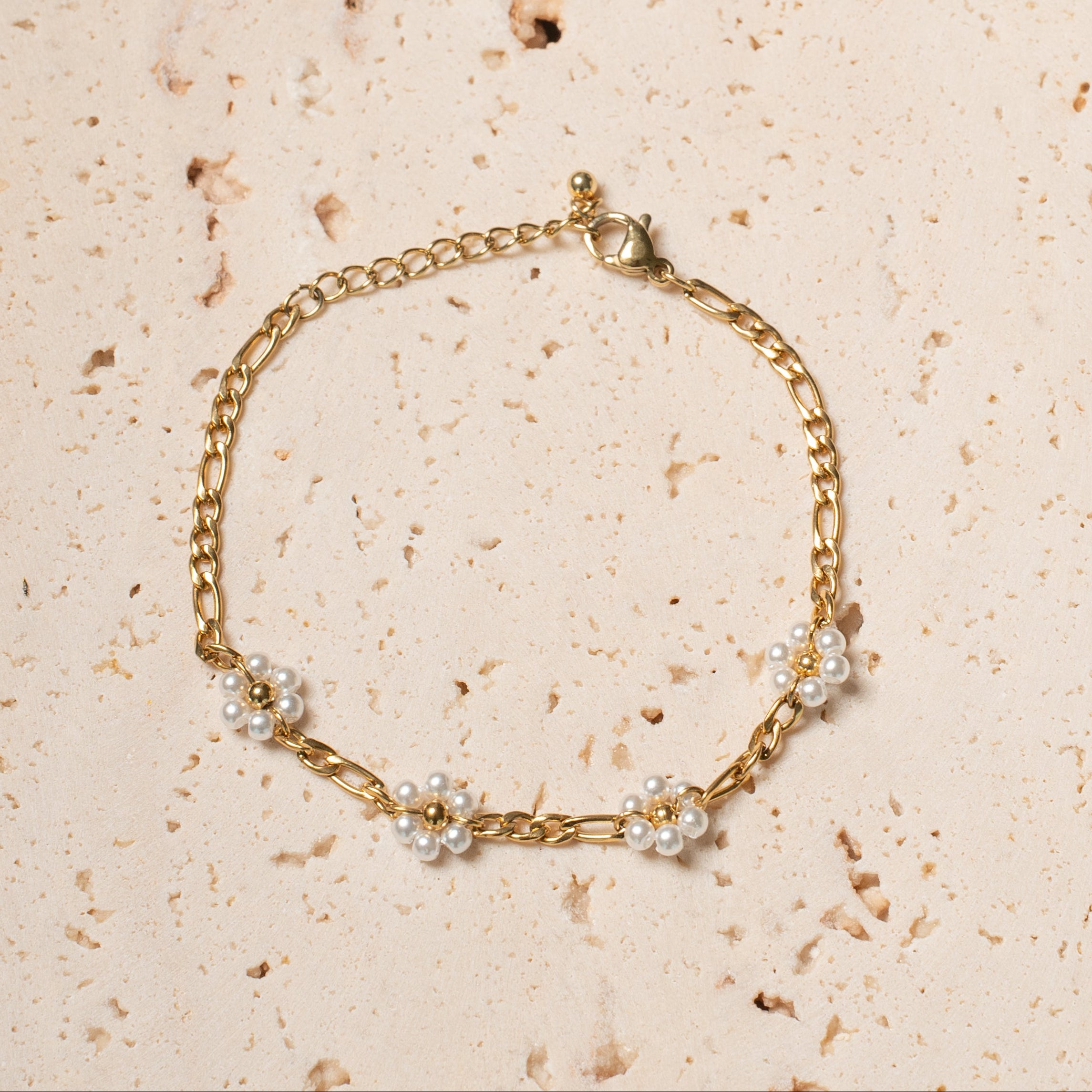 Camilla Armband in gold mit feiner Gliederkette und kleinen Blumen aus weissen Kunststoffperlen.