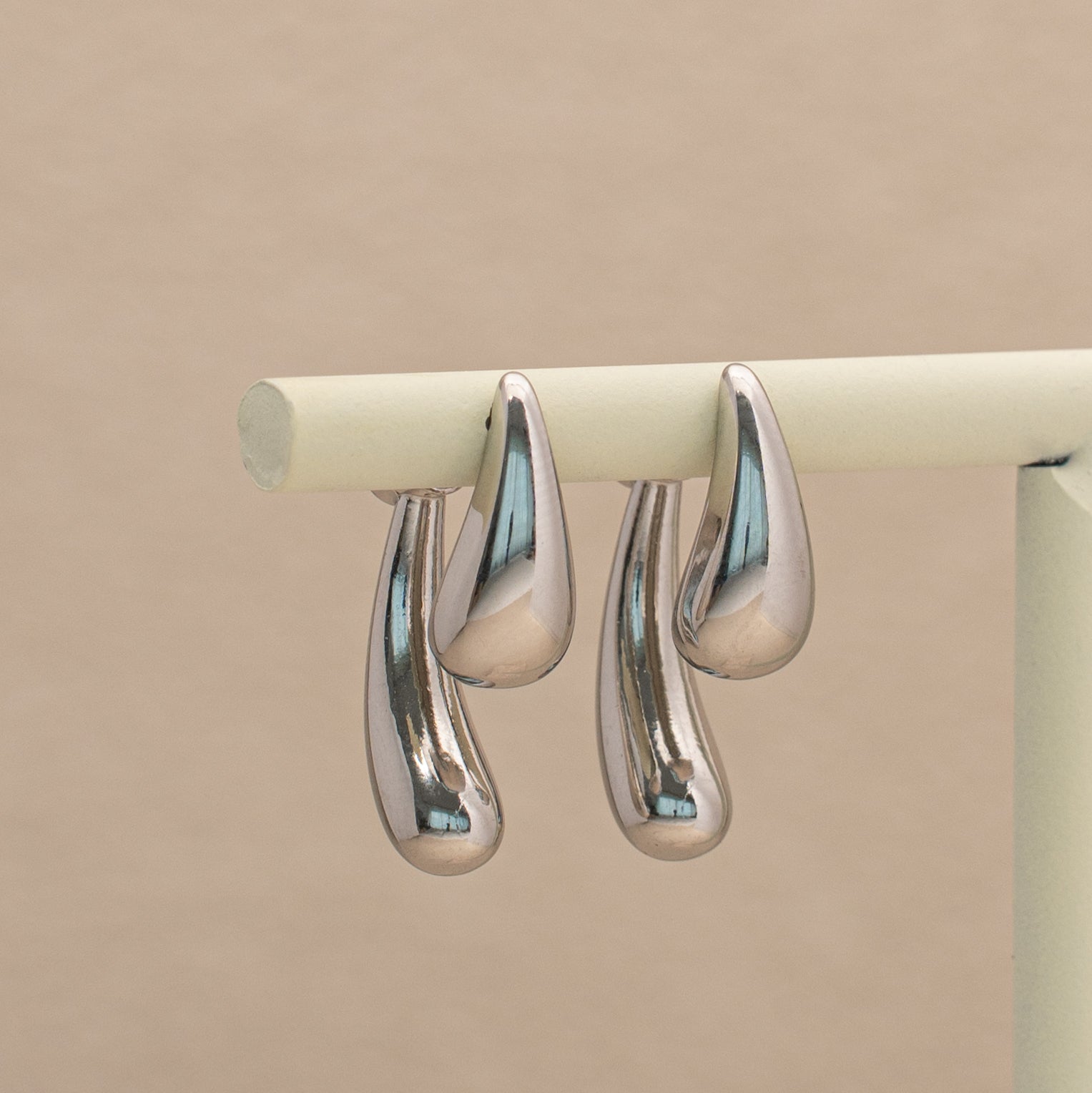 Kuro Ohrstecker in silber mit zwei glatten Tropfen, hängend an einem Display.