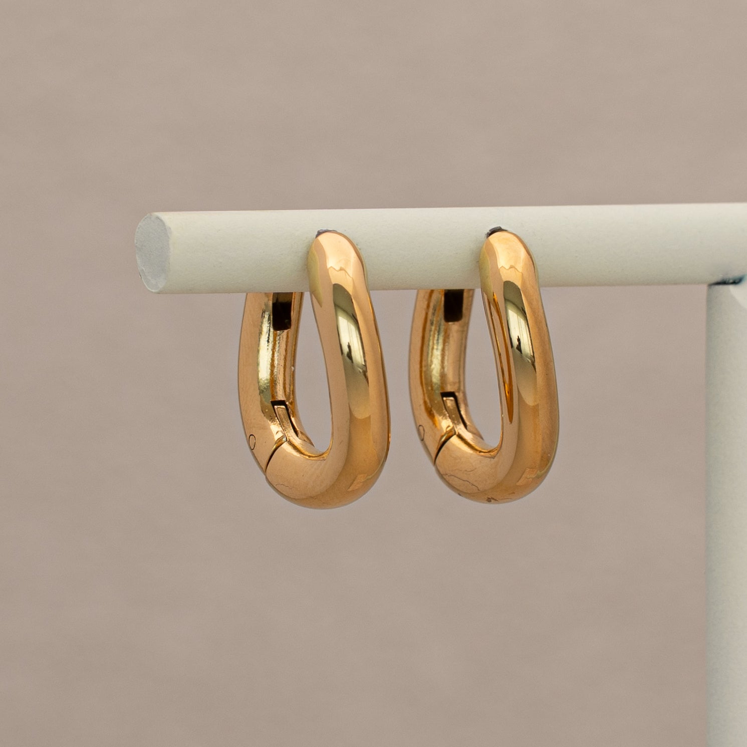 Leffa Creolen in gold mit kurviger Form, hängend an einem Display.