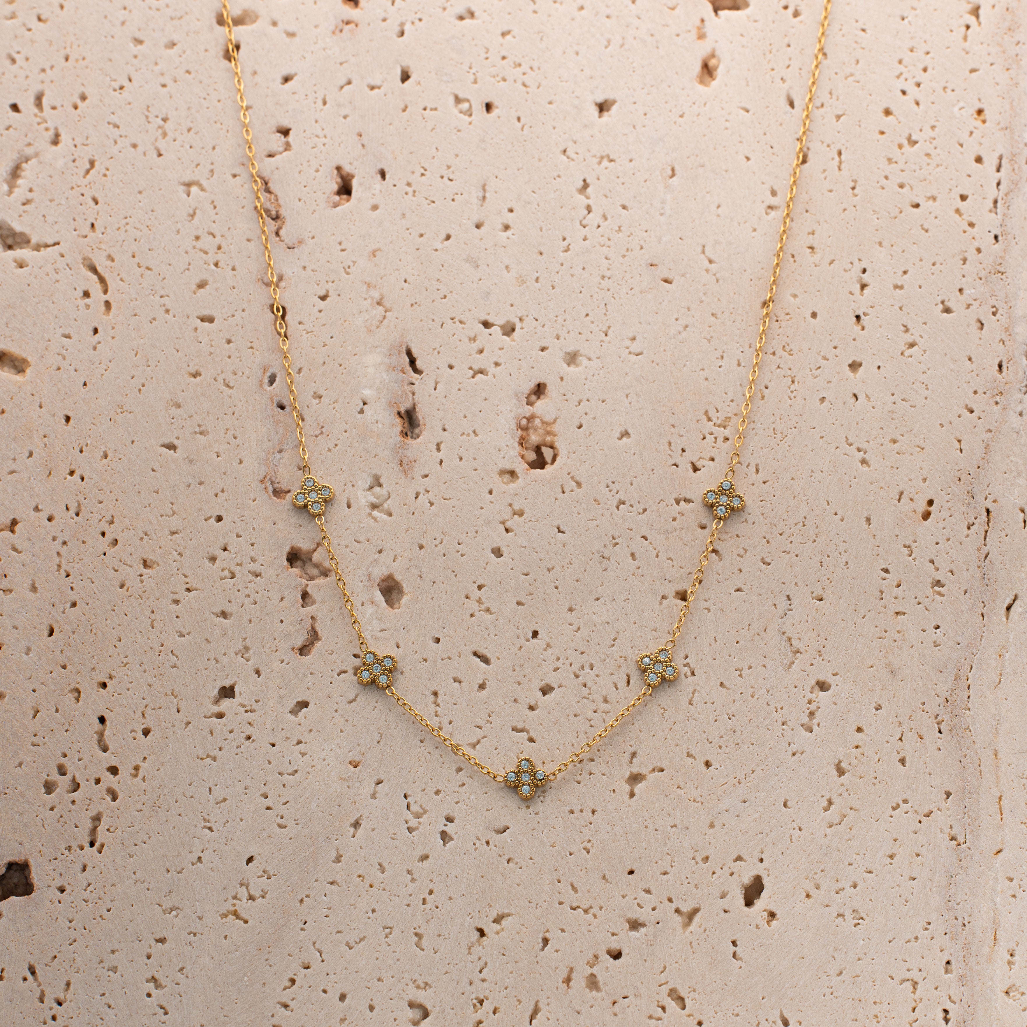 Liana Halskette in gold mit einer filigranen Kette und fünf eingereihten mit Steinen besetzten Kleeblättern.