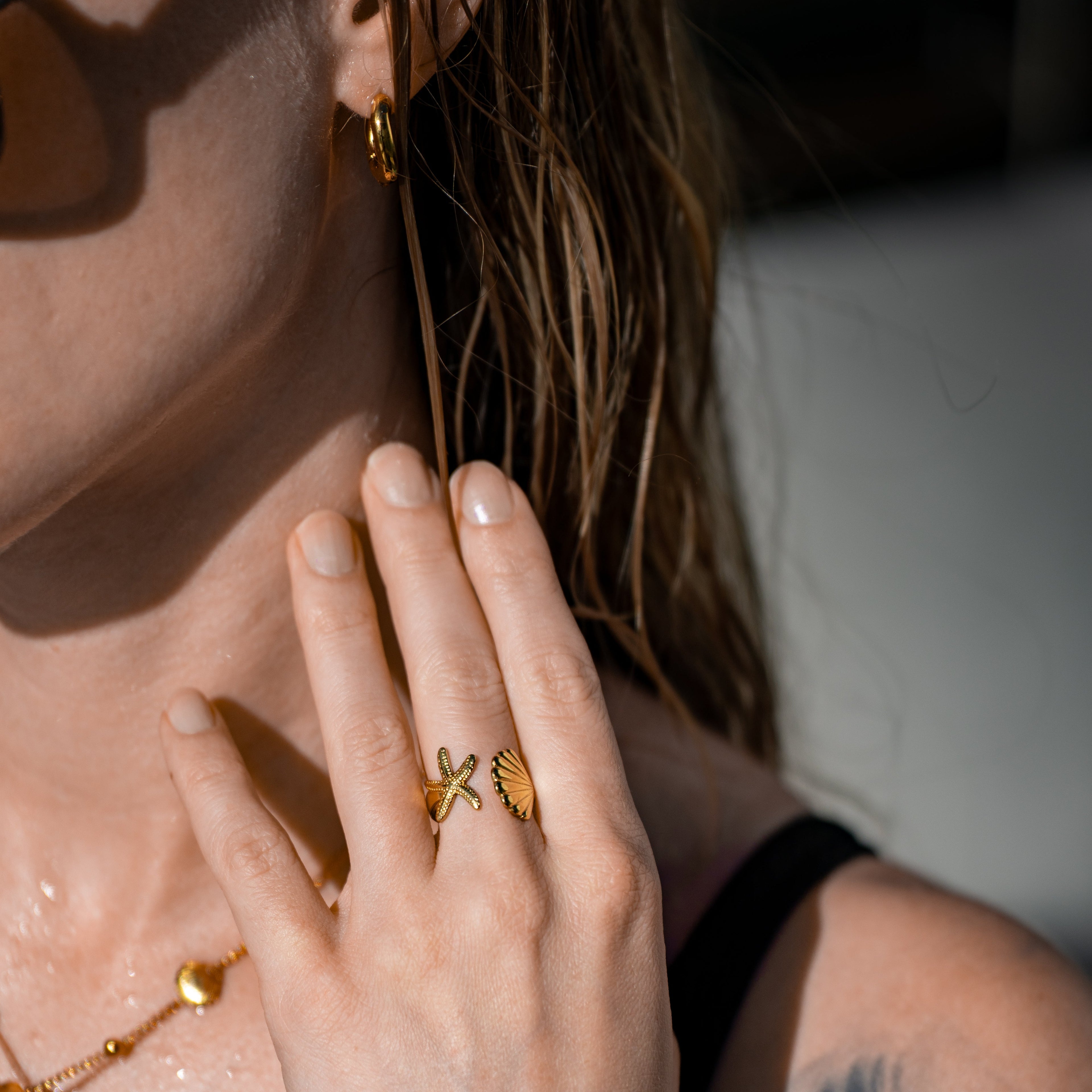 Merida Ring in Gold mit einer Muschel und einem Seestern, getragen an einer Hand.