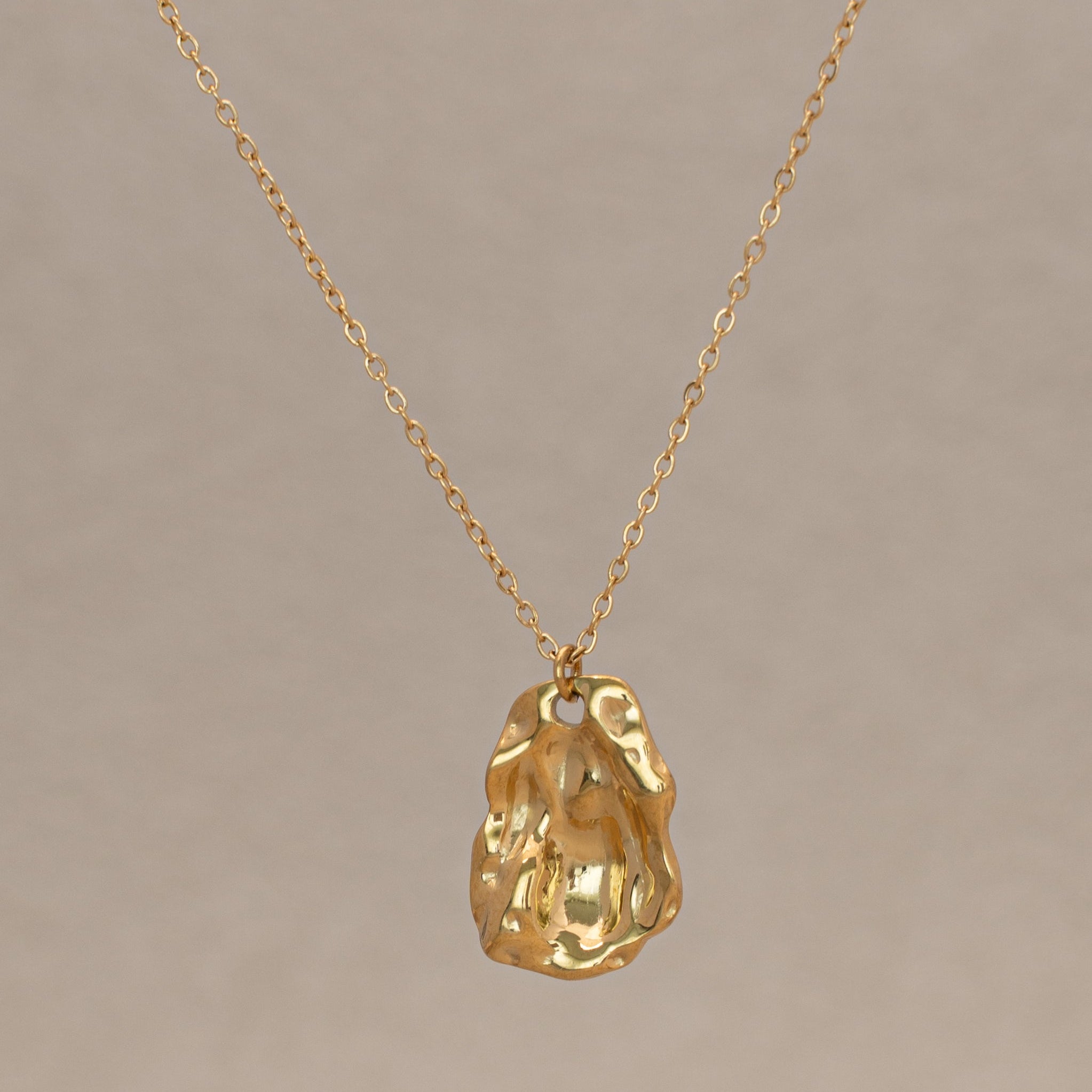 Molten Halskette in gold mit einer filigranen Kette und einem organisch geformten Anhänger.