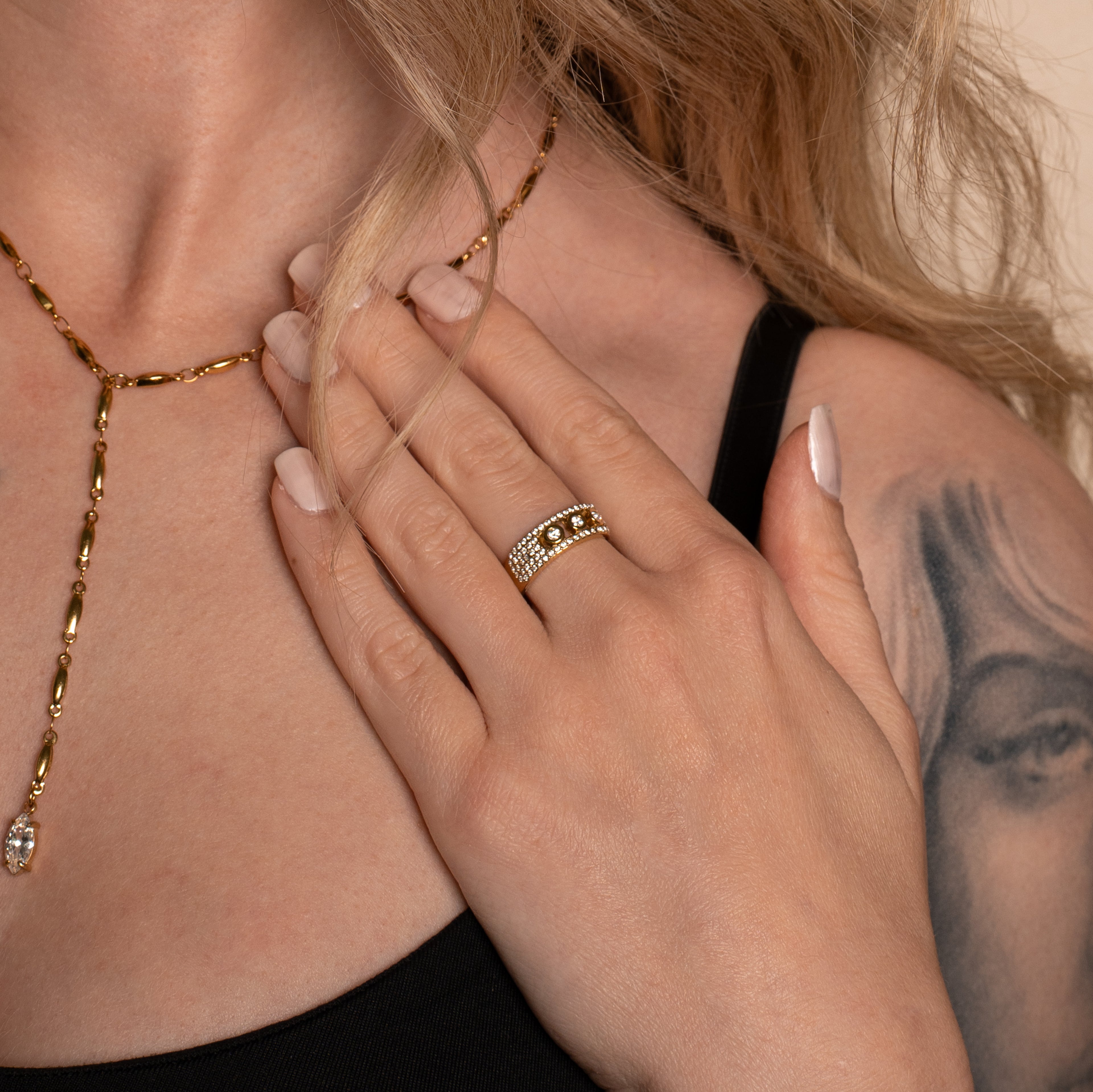 Frau trägt den Noelle Ring in Gold, mit Steinen besetztes Band mit drei grösseren Steinen in der Mitte.