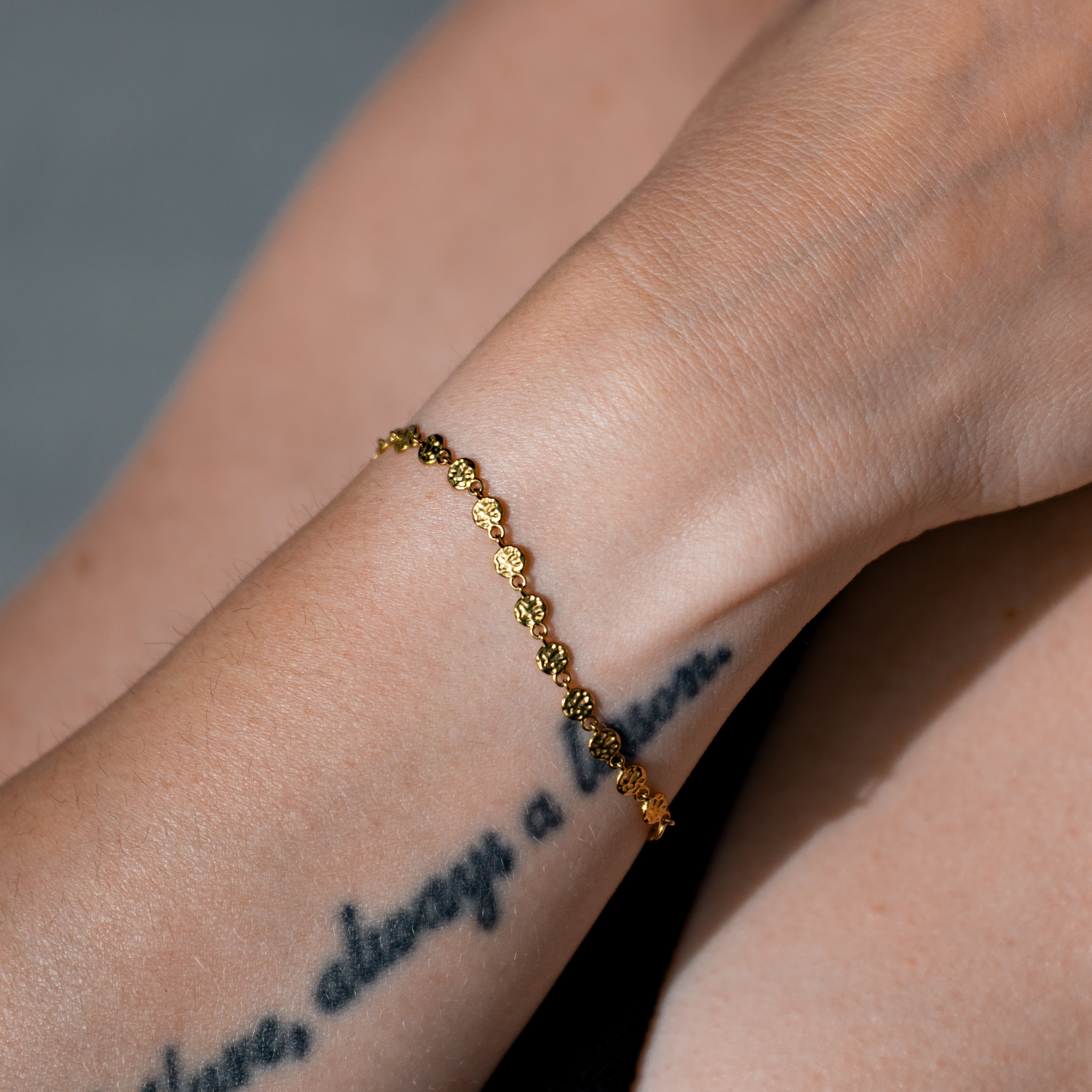 Rumi Armband mit einer Kette bestehend auf kleinen unregelmässigen Scheiben, getragen an einer Frau.
