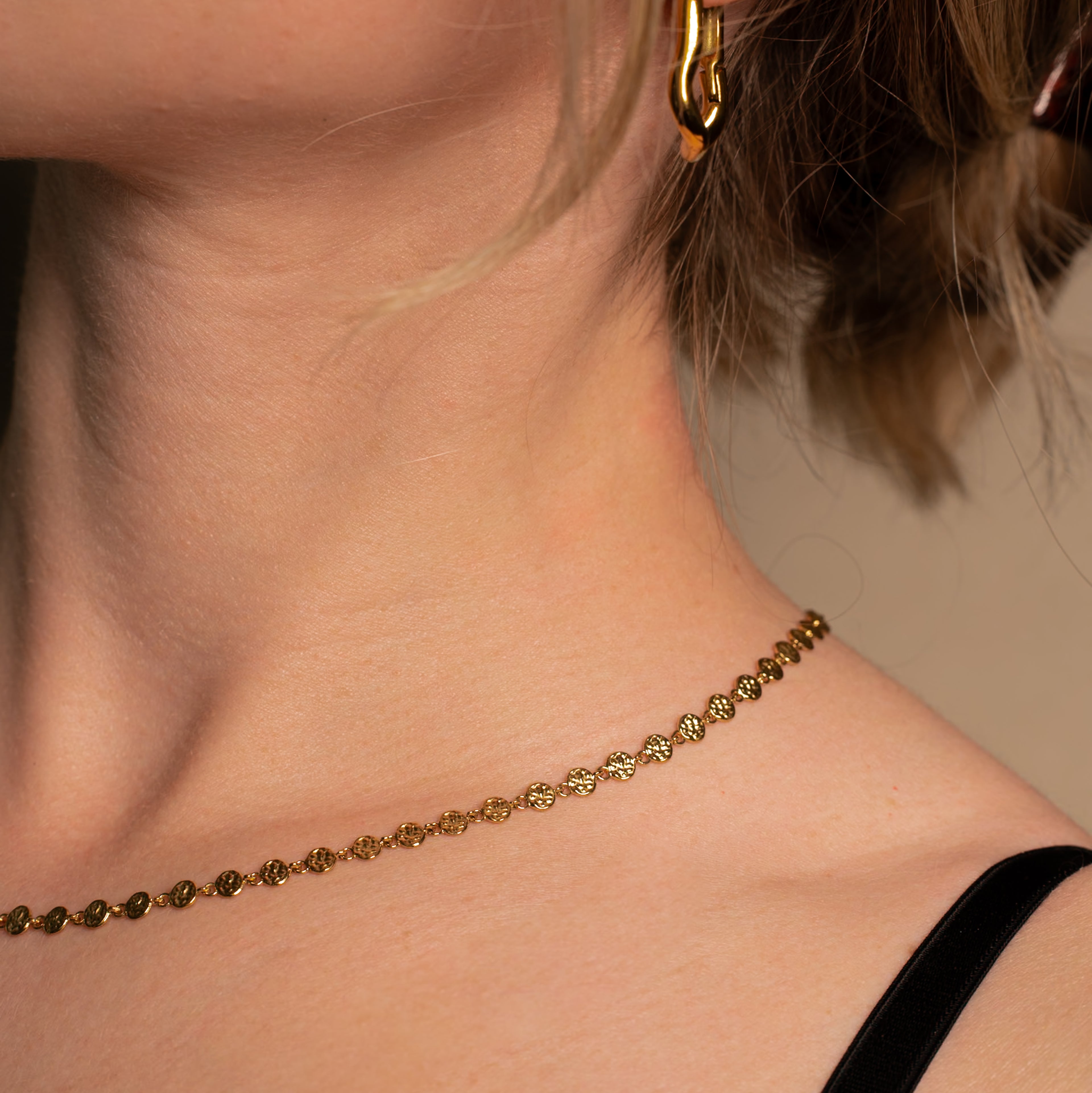 Frau trägt die Rumi Halskette in gold bestehend aus einer Kette mit kleinen unregelmässigen Scheiben.