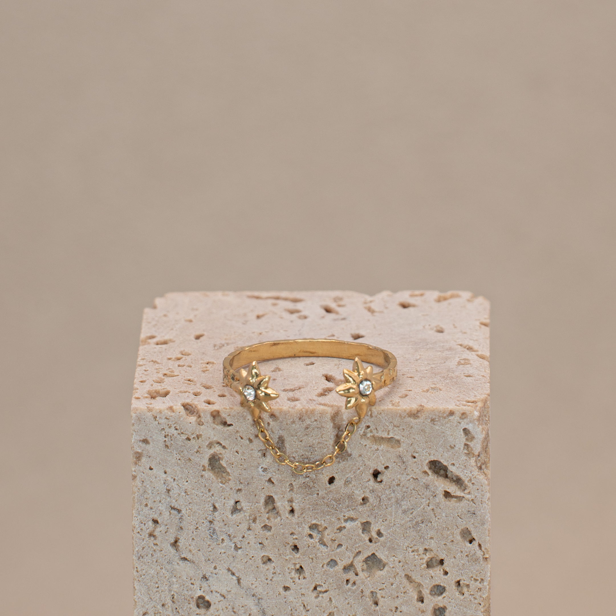 Stella Ring in gold, offene Form mit zwei mit Steinen besetzten Sternen, verbunden mit einer dünnen Kette.