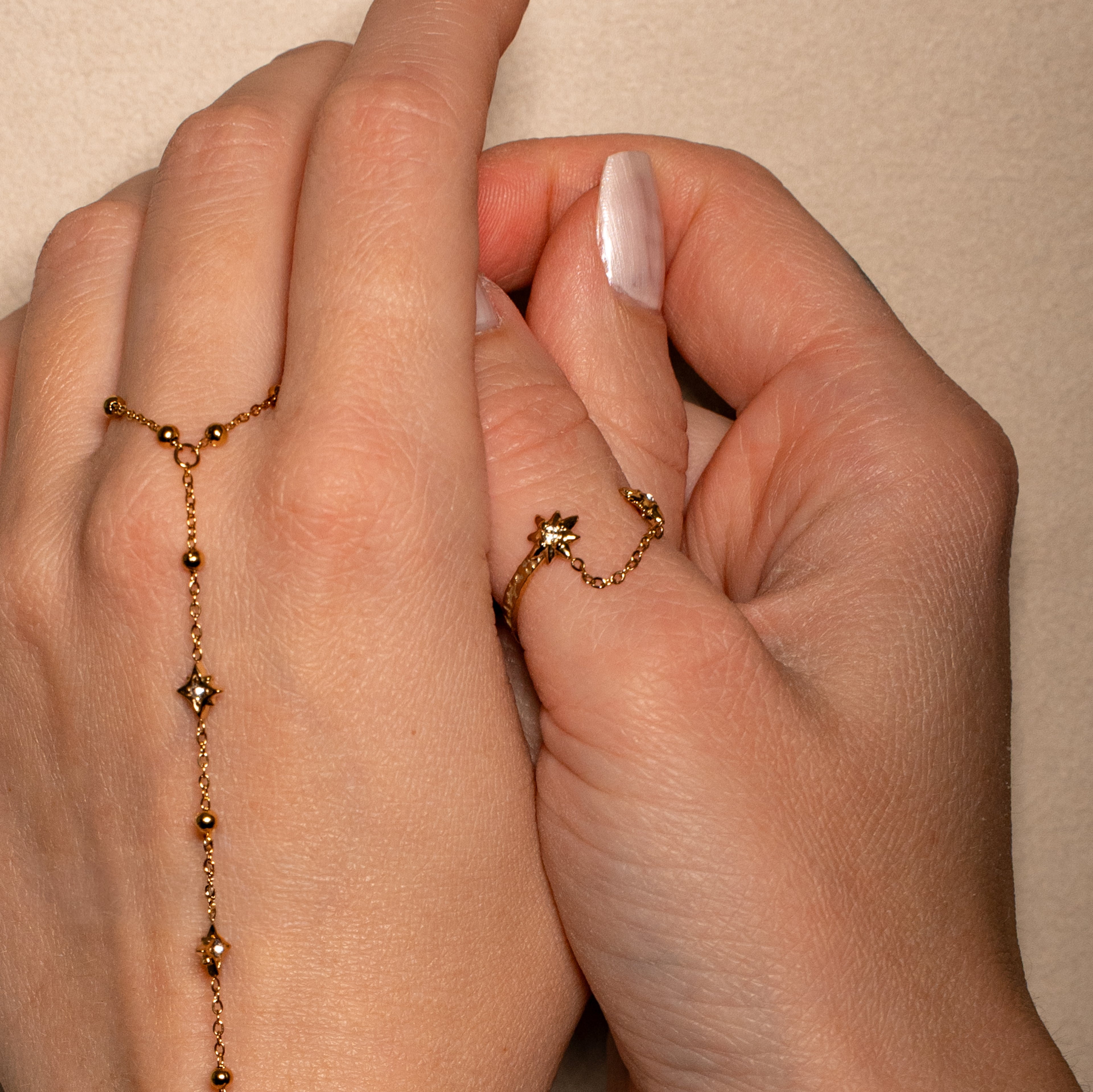Stella Ring in gold, offene Form mit zwei mit Steinen besetzten Sternen, verbunden mit einer dünnen Kette.
