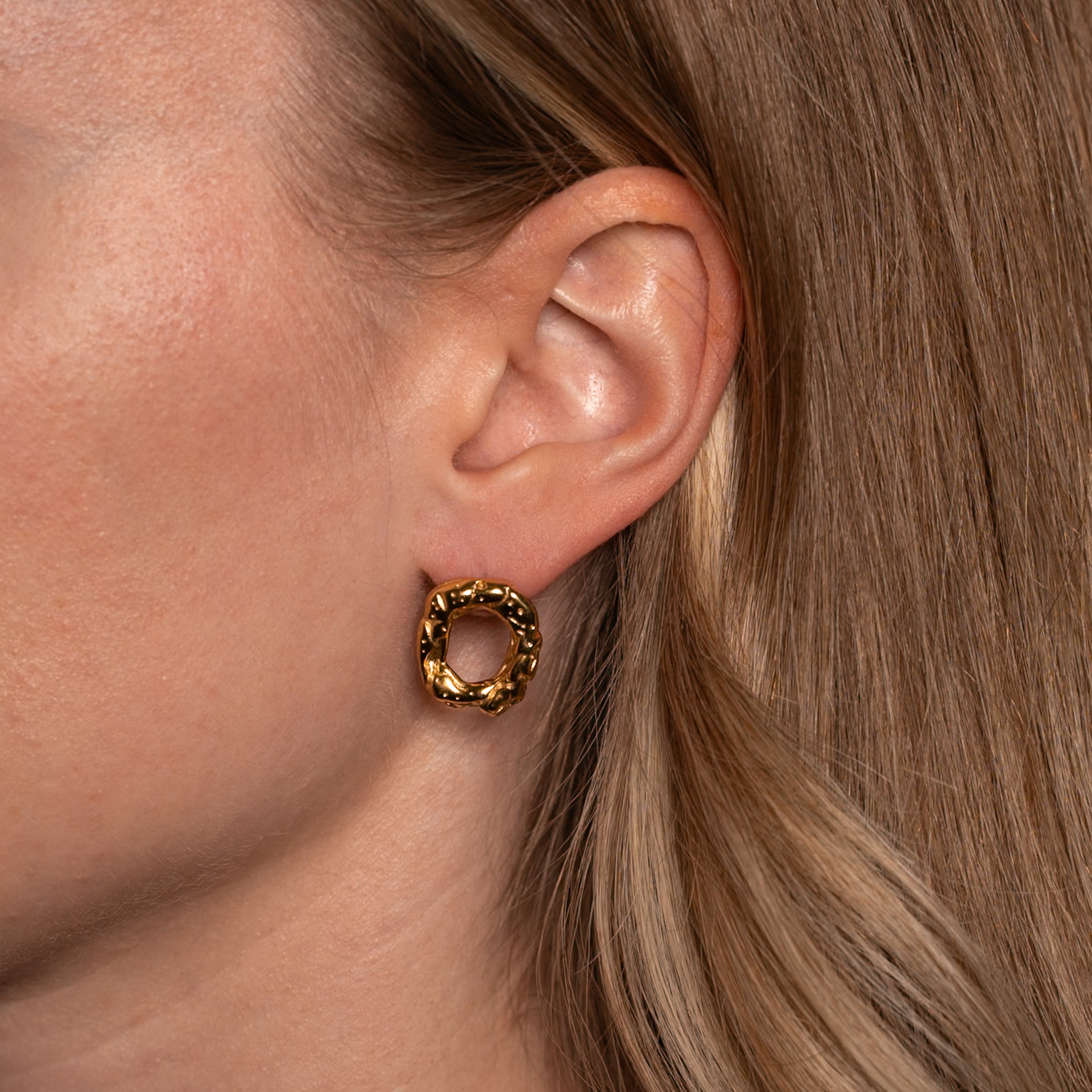 Frau trägt die Tova Ohrringe in gold, Stecker mit organischer Donut-Form.